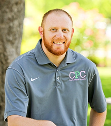 Chiropractor Alex Lee smiling in a grey shirt.