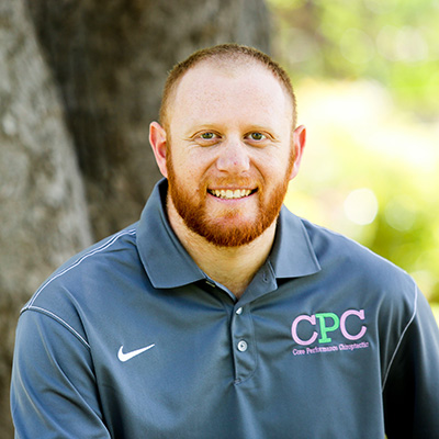 Chiropractor Alex Lee smiling outside in front of a tree.